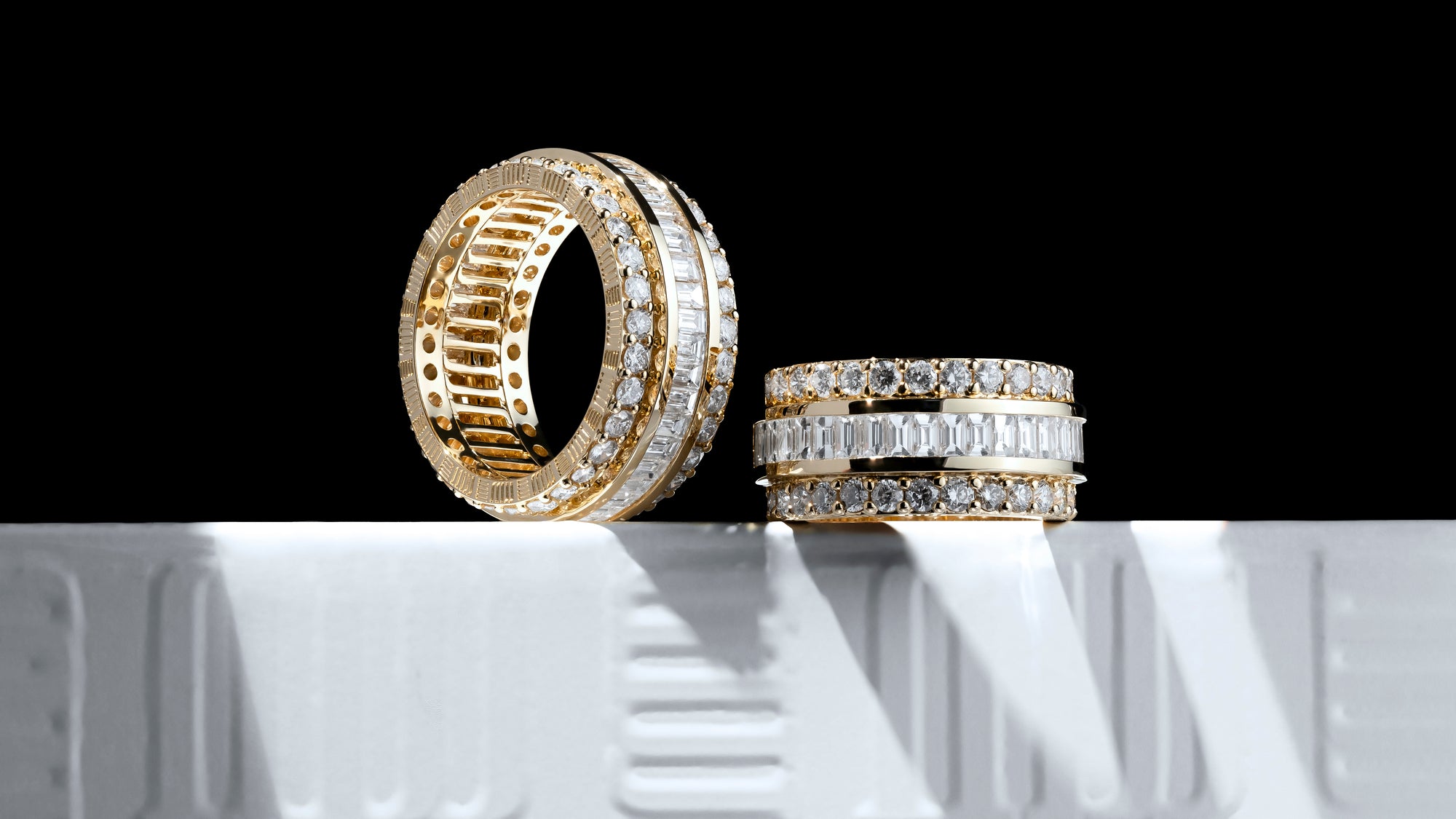 Gold and diamond-studded rings by MJ Jones, showcasing luxury craftsmanship and customisable design. Featuring a mix of brilliant-cut and baguette-cut diamonds, these elegant rings are crafted for those seeking high-quality jewellery with a modern touch. Perfect for fine jewellery enthusiasts looking for bespoke and unique diamond pieces.